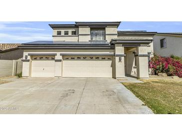 Two-story home featuring a three-car garage, concrete driveway, solar panels, and manicured landscaping at 14754 W Amelia Ave, Goodyear, AZ 85395