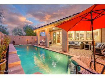 Inviting backyard pool with covered patio, lounge area, and lush landscaping, perfect for outdoor entertaining and relaxation at 15796 W Shaw Butte Dr, Surprise, AZ 85379