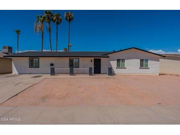 Charming single-story home featuring a fresh white brick exterior and a well-maintained front yard with mature palm trees at 3802 W Mission Ln, Phoenix, AZ 85051