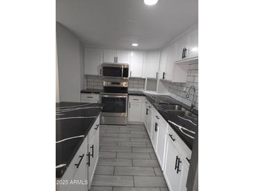 Updated kitchen featuring stainless steel appliances, white cabinets, subway tile backsplash, and gorgeous black-and-white counters at 4043 W Palomino Rd, Phoenix, AZ 85019