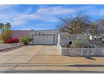 Charming home features a two-car garage, mature landscaping, and a well-maintained yard, with a white lattice fence at 6441 E Colby St, Mesa, AZ 85205