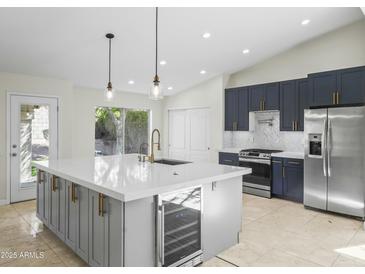 Bright kitchen features a large center island with seating, quartz countertops, wine fridge, and stainless steel appliances at 6920 W Via Montoya Dr, Glendale, AZ 85310