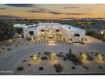 Elegant modern home with desert landscaping, sophisticated lighting, and a private driveway, creating a welcoming ambiance at 8245 E Via Del Sol Dr, Scottsdale, AZ 85255