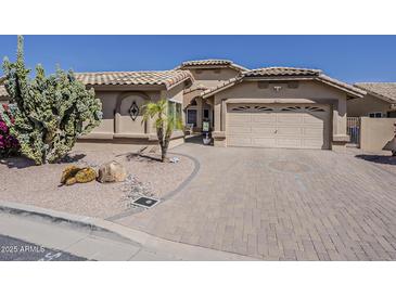 Charming single-story home with a tile roof, desert landscaping, and a brick driveway at 14334 W Shawnee Trl, Surprise, AZ 85374