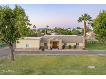 Sprawling single-story home with large lawn, desert landscaping, and stone accents on the facade at 1438 E Mesquite St, Gilbert, AZ 85296