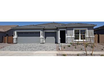 Charming single-story home with a gray color scheme, brick accents, three-car garage, and stone driveway at 24152 N 172Nd Ave, Surprise, AZ 85387