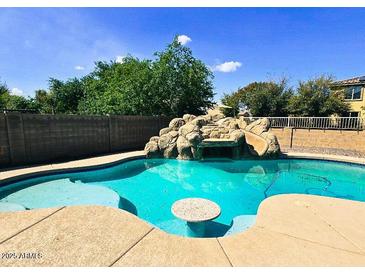 Backyard pool boasts a rock waterfall feature and swim-up table at 24228 S 211Th St, Queen Creek, AZ 85142