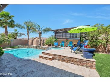 Stunning backyard oasis featuring a sparkling pool, spa, stone accents, and comfortable lounge seating at 2468 W Dapple Gray Ct, San Tan Valley, AZ 85144