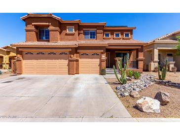 Two-story home showing desert landscaping, a covered porch, and a three-car garage at 1690 E Desert Breeze Ct, Casa Grande, AZ 85122