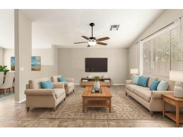Bright living room features neutral tones, ceiling fan, and large windows for natural light at 21840 N 41St St, Phoenix, AZ 85050