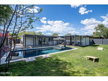 Inviting backyard features a sparkling pool, grassy area, and covered lounge space at 5809 N 10Th Pl, Phoenix, AZ 85014