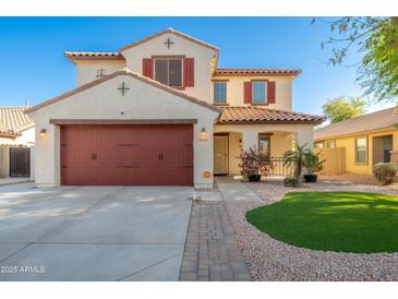 Charming two-story home with a red door garage, decorative shutters, and well-manicured landscaping at 14095 W Larkspur Dr, Surprise, AZ 85379