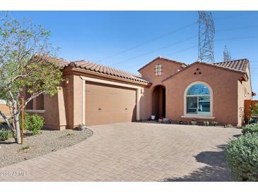 Charming single-story home featuring a tile roof, arched window and a brick-paved driveway and walkway at 26049 W Matthew Dr, Buckeye, AZ 85396