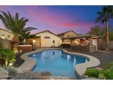 Inviting backyard pool area with outdoor kitchen, hot tub and palm trees at 2810 N 112Th Ln, Avondale, AZ 85392