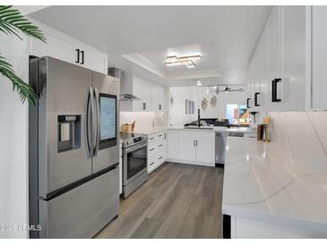 This bright kitchen has stainless steel appliances, white cabinets and quartz countertops at 3401 N 37 St # 14, Phoenix, AZ 85018