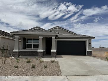 Charming single-story home featuring stone accents, a black garage door, and desert landscaping in the front yard at 46378 W Lander Ln, Maricopa, AZ 85139
