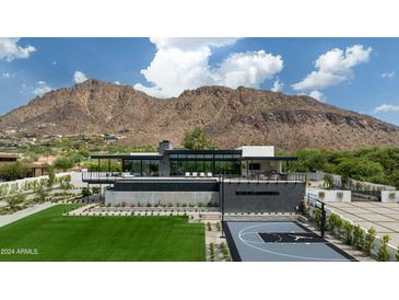 Grand modern home with a luxurious pool and basketball court set against a mountain backdrop at 5814 E Camelback Rd, Phoenix, AZ 85018