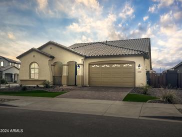 Charming single-story home featuring a tile roof, brick driveway, and well-maintained landscaping at 15911 W Montana De Oro Dr, Surprise, AZ 85387