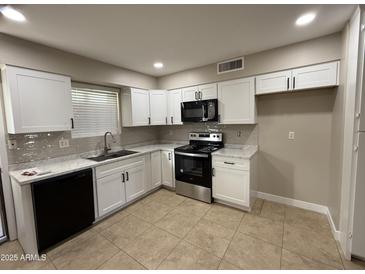 Modern kitchen featuring white cabinets, stainless steel appliances, and tile flooring at 3314 W Del Monico Ln, Phoenix, AZ 85051