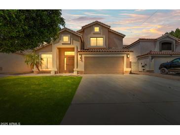 Charming two-story home featuring a well-manicured lawn, mature trees, and a spacious driveway leading to an attached garage at 332 N Cobblestone St, Gilbert, AZ 85234