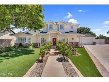 Inviting home with a red door, lush lawn, and beautiful landscaping in a desirable neighborhood at 645 S 54Th St, Mesa, AZ 85206