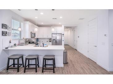 Bright kitchen with white cabinets, stainless steel appliances, and a quartz countertop island with seating at 17244 W West Wind Dr, Surprise, AZ 85387