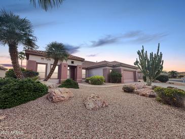 Charming single-story home with desert landscaping, rocks, and mature palm trees at 19982 N Tealstone Dr, Surprise, AZ 85374