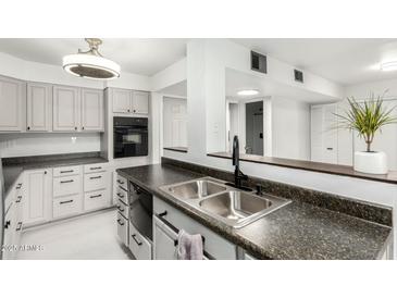 Updated kitchen features stainless steel sink, granite countertops, and white cabinets at 540 N May -- # 1075, Mesa, AZ 85201