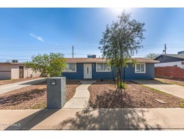 Charming single-story home with blue exterior, landscaped front yard, and a welcoming walkway to the front door at 6033 S 19Th Pl, Phoenix, AZ 85042