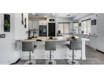 Bright kitchen with white cabinets, marble countertops, breakfast bar, and modern stainless steel appliances at 17451 W Hadley St, Goodyear, AZ 85338