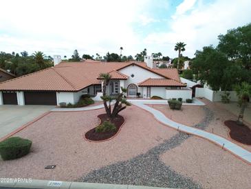 Aerial view of home with tile roof, desert landscaping, and a three car garage at 13631 N 70Th Dr, Peoria, AZ 85381