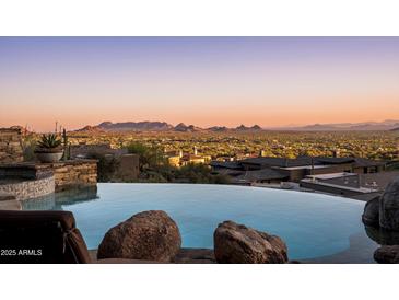 Infinity pool showcasing picturesque views of the city and mountains at twilight at 42572 N 108Th St, Scottsdale, AZ 85262