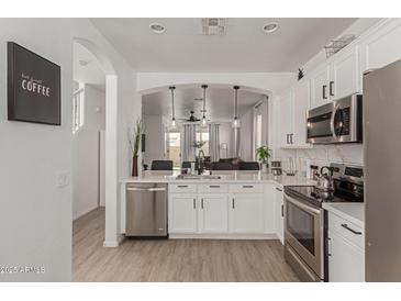 Bright white kitchen featuring stainless steel appliances and an open design that connects to the living room at 11979 W Pierce St, Avondale, AZ 85323