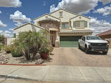 Inviting two-story home featuring a stone accent facade, a green two-car garage door, and lush landscaping at 1350 E Racine Dr, Casa Grande, AZ 85122