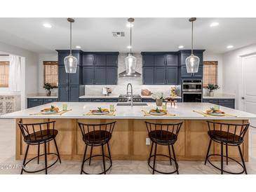 A stylish kitchen features a large island with seating and pendant lighting at 21341 S 227Th Way, Queen Creek, AZ 85142