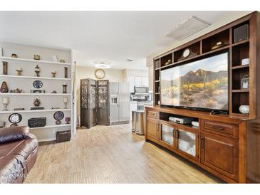 Cozy living room featuring wood floors, built in shelving, and a large entertainment center at 9021 W Elm St # 7, Phoenix, AZ 85037