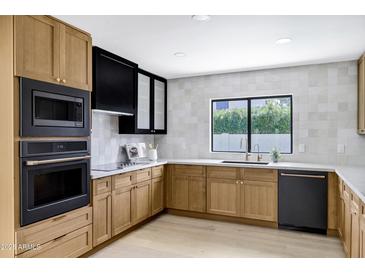 Bright kitchen featuring sleek, modern appliances, light wood cabinets, and white marble countertops at 8019 E Del Timbre Dr, Scottsdale, AZ 85258