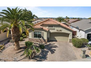 Charming home with a tile roof, desert landscaping, and a paved driveway at 18058 W Weatherby Dr, Surprise, AZ 85374