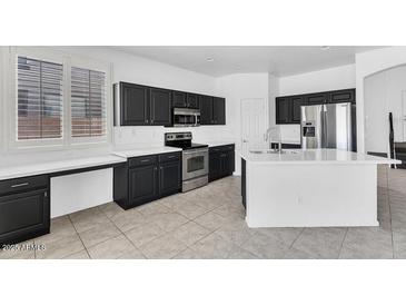 Modern kitchen with black cabinets, stainless steel appliances, and a bright island at 18525 N Larkspur Dr, Maricopa, AZ 85138