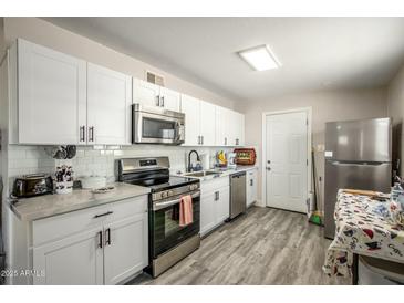Modern kitchen features white cabinets, stainless steel appliances, and stylish gray flooring at 2221 E Lynne Ln, Phoenix, AZ 85042