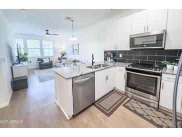 Modern kitchen with stainless steel appliances, granite countertops, and an open layout overlooking the living room at 2314 E Hidalgo Ave, Phoenix, AZ 85040