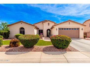 Charming single-story home featuring a well-manicured lawn and beautiful desert landscaping at 2553 E Carob Dr, Gilbert, AZ 85298