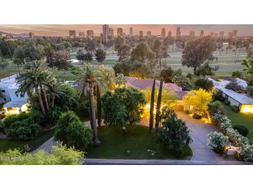 Stunning aerial view of property, showcasing lush landscaping, mature trees, and city skyline at sunset at 3006 N Manor W Dr, Phoenix, AZ 85014