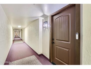 Long hallway with textured walls leading to a brown door marked with '301' and a visible doorbell at 7930 E Camelback Rd # 301, Scottsdale, AZ 85251