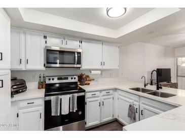 Modern kitchen features white cabinetry, stainless steel appliances, and sleek countertops at 12201 S Paiute St, Phoenix, AZ 85044