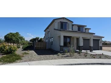 Two-story home with beige stucco, rock landscaping, covered porch and grey two-car garage under a clear blue sky at 19117 W Missouri Ave, Litchfield Park, AZ 85340