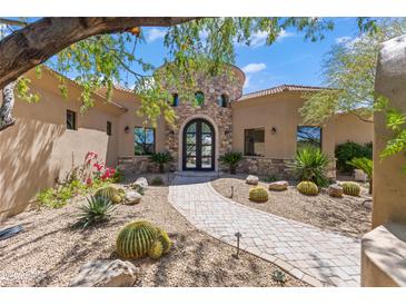 Stunning custom home with a stone tower, barrel tile roof, landscaped yard, and welcoming walkway to the arched entry door at 37334 N Winding Wash Trl, Carefree, AZ 85377