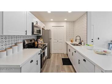 Modern kitchen features white cabinets, quartz countertops, stainless steel appliances, and decorative backsplash at 623 W Guadalupe Rd # 288, Mesa, AZ 85210