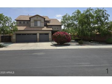 Two-story home with a three car garage, mature landscaping, and neutral colored paint at 12237 W Sherman St, Avondale, AZ 85323
