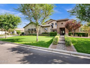 Beautiful exterior of home with lush green lawn, mature trees, and a charming brick entryway at 17937 E Colt Ct, Queen Creek, AZ 85142